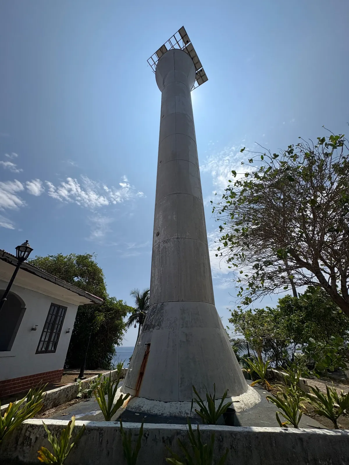 Newest tall white lighthouse at Cape San Agustin Parola with a solar panel on top, seen from below against a blue sky