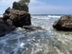 Offshore rock formation topped with trees and waves rolling over clear shallow water at Cape San Agustin in Governor Generoso, Davao Oriental