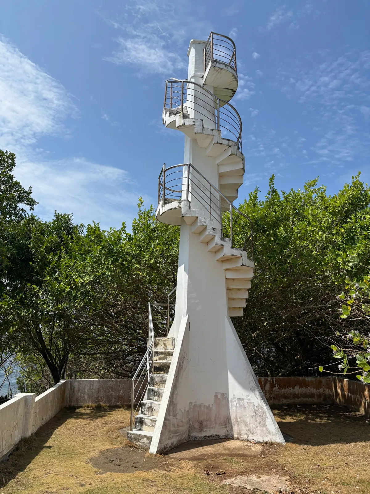 Oldest lighthouse at Cape San Agustin Parola with an exterior spiral staircase and railings under a blue sky
